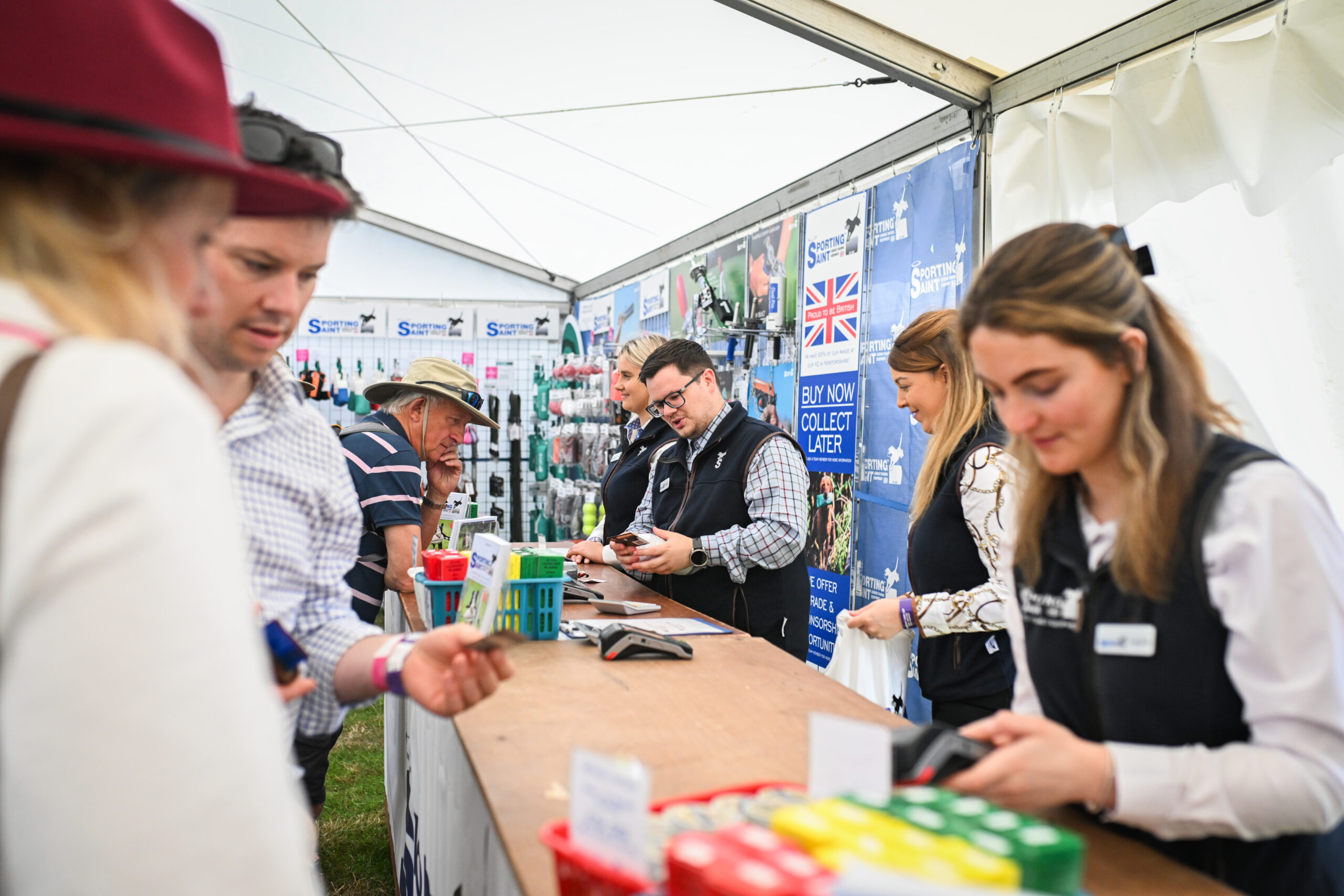 Staff serve customers behind the counter of the Sporting Saint stand at The Game Fair.
